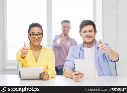 business, office and startup concept - creative smiling team with tablet pc computers at office showing thumbs up