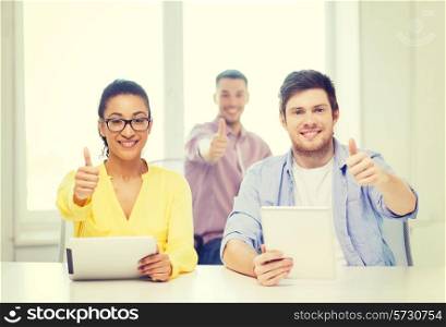 business, office and startup concept - creative smiling team with tablet pc computers at office showing thumbs up