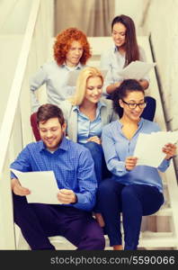 business, office and startup concept - smiling creative team with papers and take away coffee on staircase