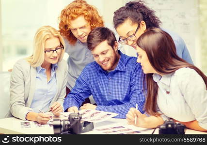 business, office and startup concept - smiling creative team with photocameras and images working in office