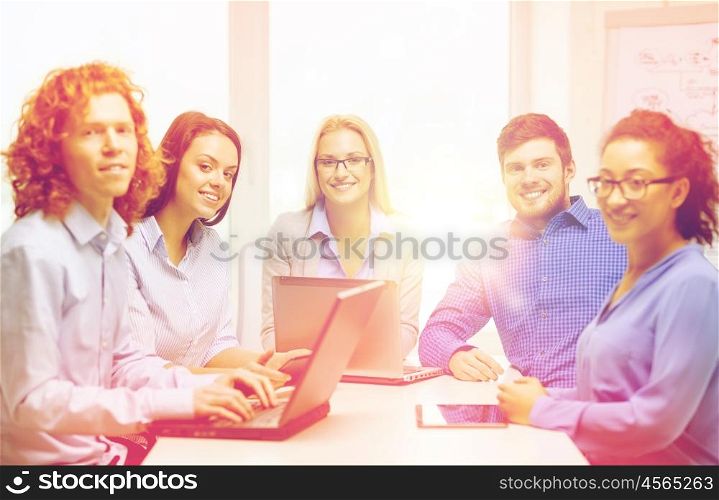 business, office and startup concept - smiling creative team with table pc and laptop computers working in office