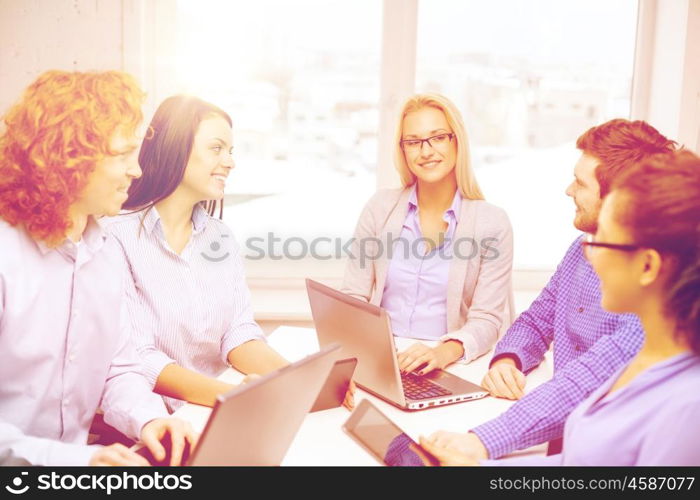 business, office and startup concept - smiling creative team with table pc and laptop computers working in office