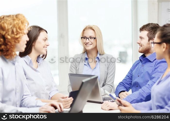 business, office and startup concept - smiling creative team with table pc and laptop computers working in office