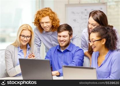 business, office and startup concept - smiling creative team with with laptop computers working in office