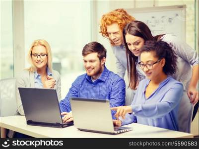 business, office and startup concept - smiling creative team with with laptop computers working in office