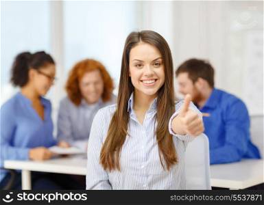 business, office and startup concept - smiling young businesswoman showing thumbs up