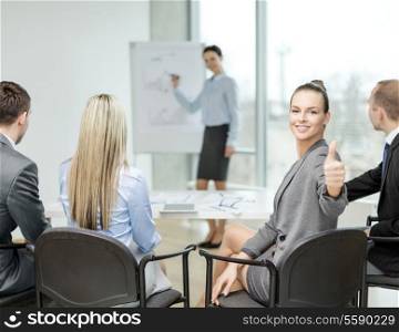 business, office and success concept - smiling businesswoman with team in office showing thumbs up