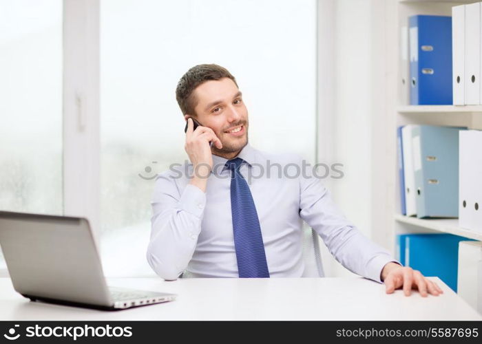 business, office and technology concept - smiling businessman with laptop computer and smartphone at office