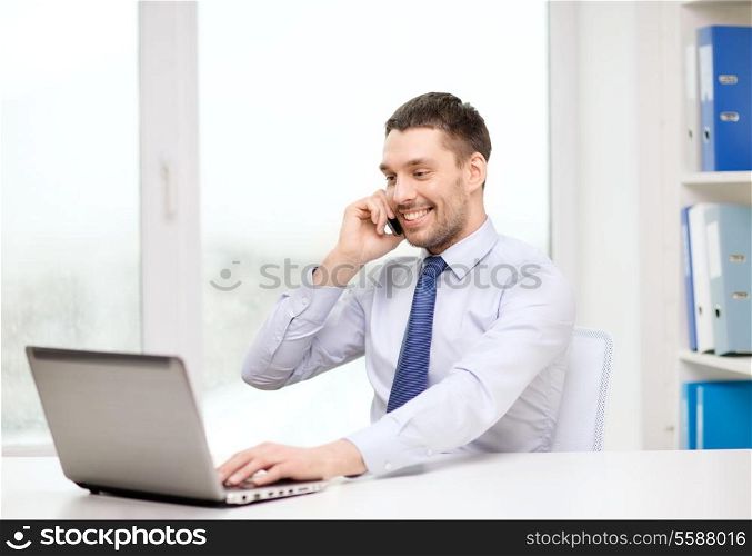 business, office and technology concept - smiling businessman with laptop computer and smartphone at office