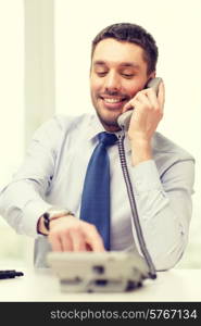 business, office and technology concept - smiling businessman with telephone dialing number at office