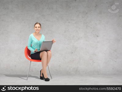 business, office and technology concept - young businesswoman sitting in chair with laptop