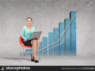 business, office and technology concept - young businesswoman sitting in chair with laptop