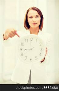 business, office and time management concept - attractive businesswoman with clock