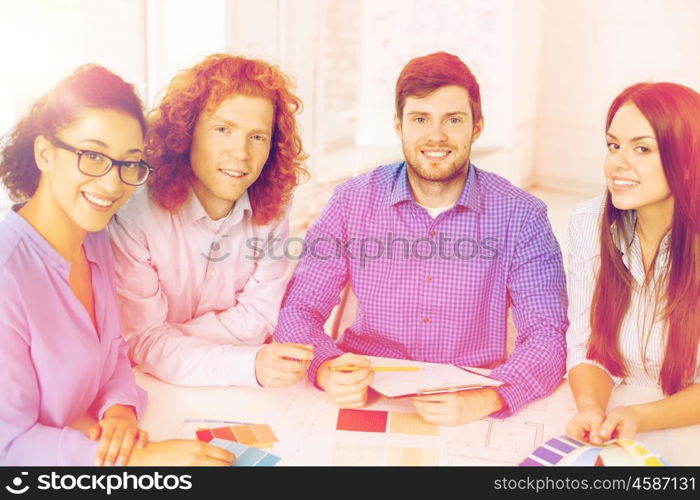 business, office, architecture and startup concept - smiling creative team with color samples and blueprint at office