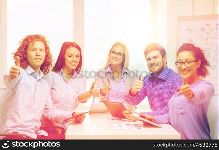 business, office, gesture and startup concep - smiling creative team with table pc computers and papers showing thumbs up in office