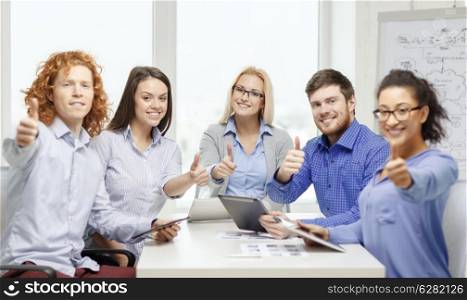 business, office, gesture and startup concep - smiling creative team with table pc computers and papers showing thumbs up in office