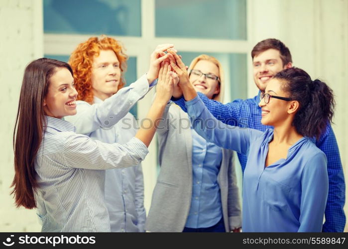 business, office, gesture and startup concept - smiling creative team doing high five gesture in office