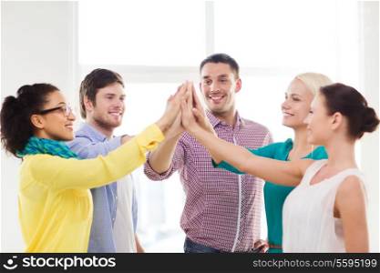 business, office, gesture and startup concept - smiling creative team doing high five gesture in office