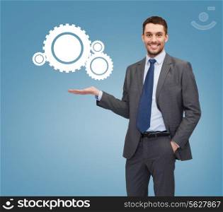 business, office, interface and people concept - smiling businessman holding settings icon on palm of his hand