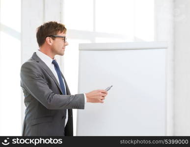 business, office, school and education concept - businessman pointing to flip board in office