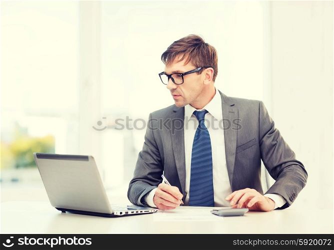 business, office, school and education concept - businessman with laptop computer, papers and calculator