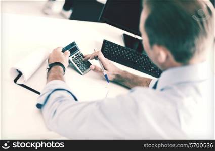 business, office, school and education concept - businessman with notebook and calculator