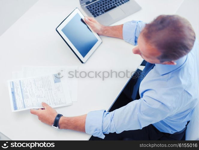 business, office, school and education concept - businessman with tablet pc and papers in office