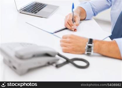 business, office, school and education concept - businessman writing in notebook