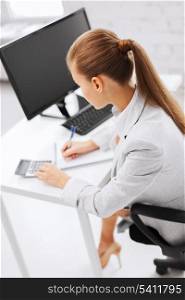 business, office, school and education concept - businesswoman with notebook and calculator