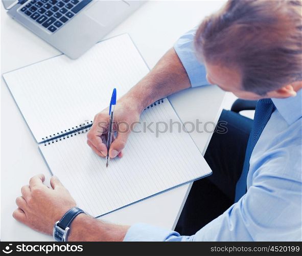 business, office, school and education concept - handsome businessman writing in notebook