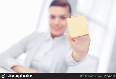 business, office, school and education concept - smiling businesswoman showing blank sticky note. smiling businesswoman showing sticky note