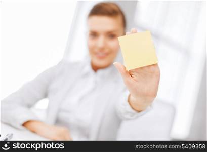 business, office, school and education concept - smiling businesswoman showing blank sticky note