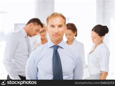 business, office, school and education concept - smiling handsome businessman with team on the back