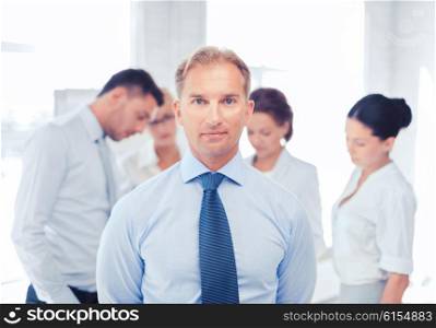 business, office, school and education concept - smiling handsome businessman with team on the back