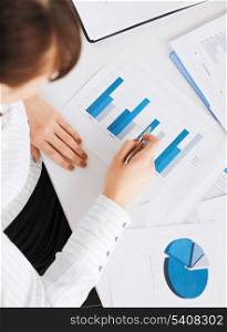 business, office, school and education concept - woman hand with charts and papers