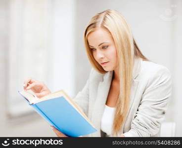 business, office, school and education concept - young woman reading book at school