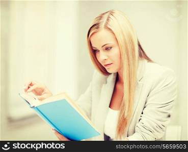 business, office, school and education concept - young woman reading book at school