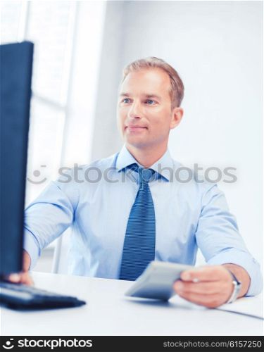 business, office, tax, school and education concept - smiling businessman with calculator, computer and papers