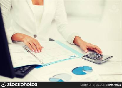 business, office, tax, school and education concept - woman hand with calculator and papers