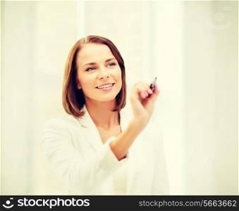 business, office, technology and education concept - smiling woman writing with pen in the air