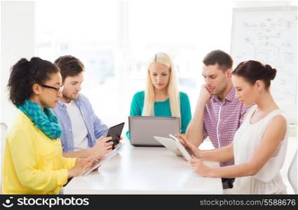 business, office, technology and startup concept - serious creative team with table pc and laptop computers working in office