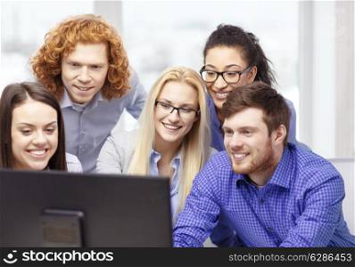 business, office, technology and startup concept - smiling business team looking at computer monitor at office