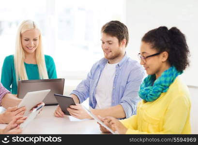 business, office, technology and startup concept - smiling creative team with table pc and laptop computers working in office