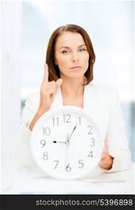 business, office, time management, deadline, school and education concept - attractive businesswoman showing clock