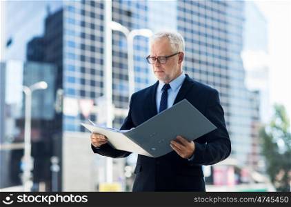 business, office work and people and concept - senior businessman paging documents in ring binder folder on city street