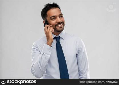 business, office worker and people concept - smiling indian businessman calling on smartphone over grey background. indian businessman calling on smartphone