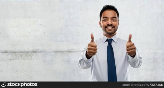business, office worker and people concept - smiling indian businessman in shirt with tie showing thumbs up over gray concrete wall background. indian businessman showing thumbs up over concrete