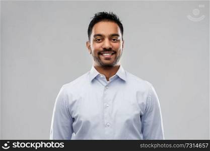 business, office worker and people concept - smiling indian businessman in shirt over grey background. indian businessman in shirt over grey background