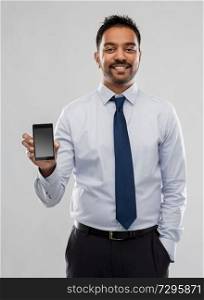 business, office worker and people concept - smiling indian businessman with smartphone over grey background. indian businessman with smartphone