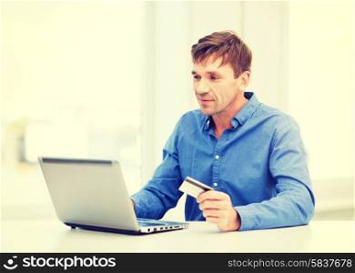 business, online banking, internet shopping concept - smiling man with laptop and credit card at home